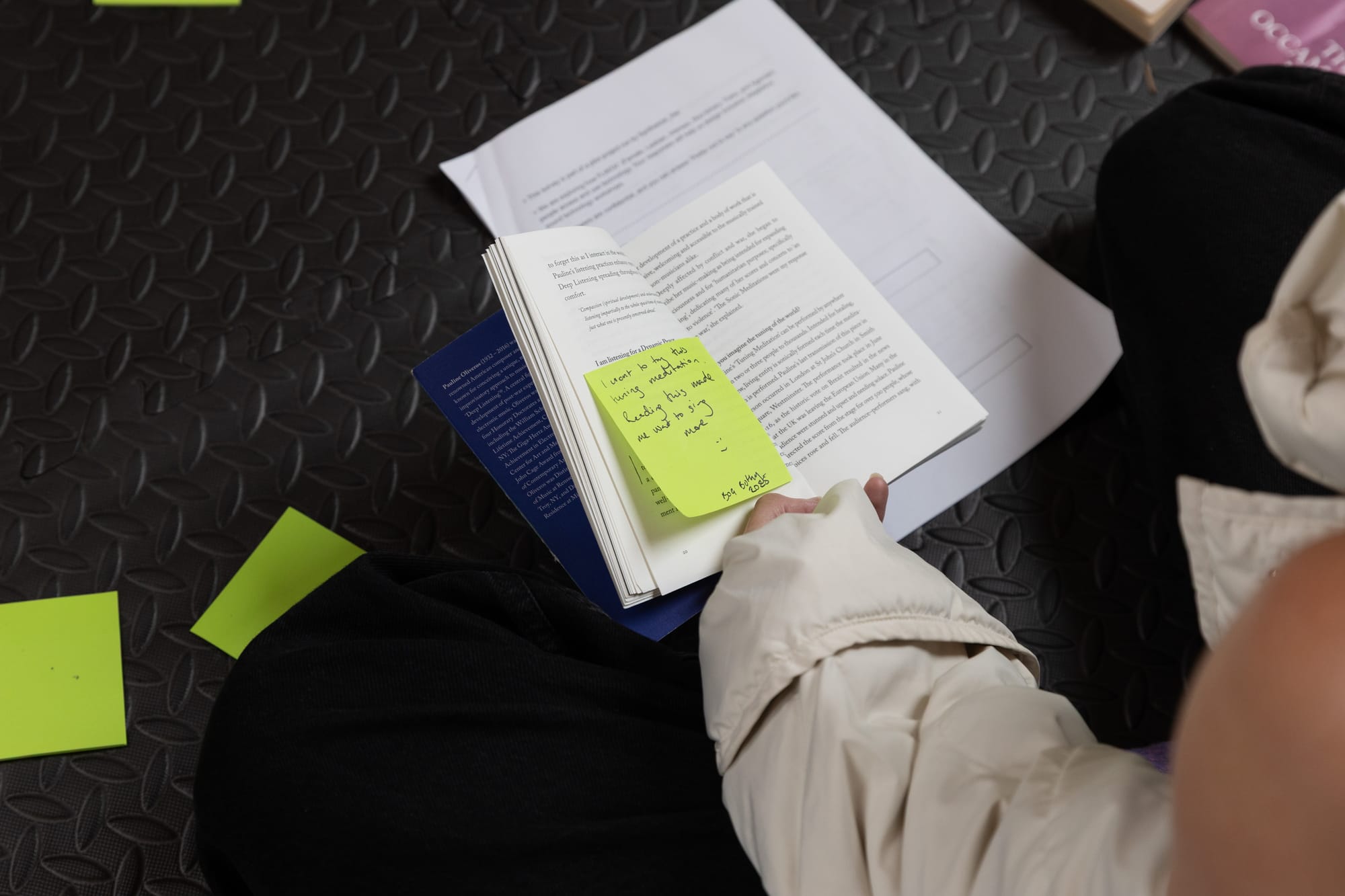 A look into the text Quantum Listening by Pauline Oliveros with a bright green post-it note stuck to it that says 'I want to try this tuning meditation. Reading this made me want to sing more :) Bog Bothy 2025'